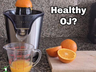 healthy oj with a juicer and sliced oranges on countertop