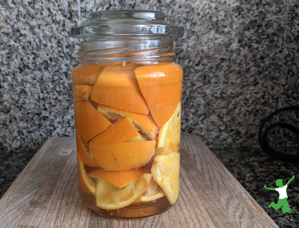orange peels in a glass jar of vinegar on granite counter
