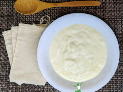 live kefir grains in white bowl with muslin bags and wooden spoon