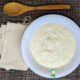 live kefir grains in white bowl with muslin bags and wooden spoon