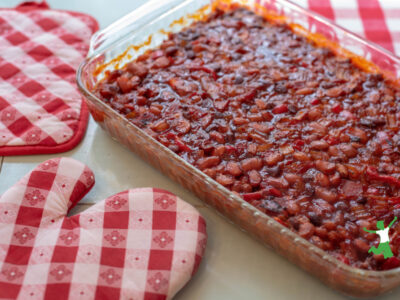 healthy baked beans casserole on kitchen counter with red and white oven mitts
