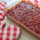 healthy baked beans casserole on kitchen counter with red and white oven mitts