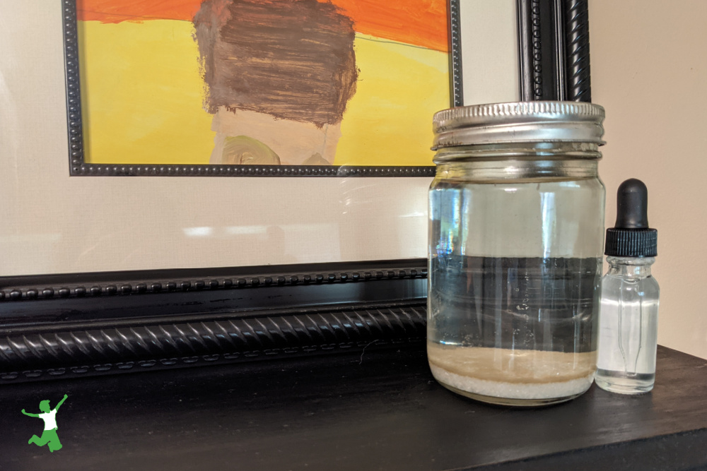 solé water solution in a glass jar and eyedropper bottle on black shelf