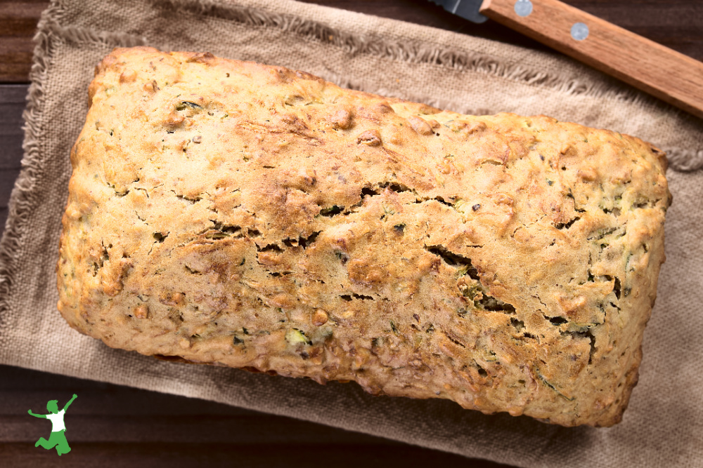 loaf of gluten-free sprouted zucchini bread cooling on beige dishtowel