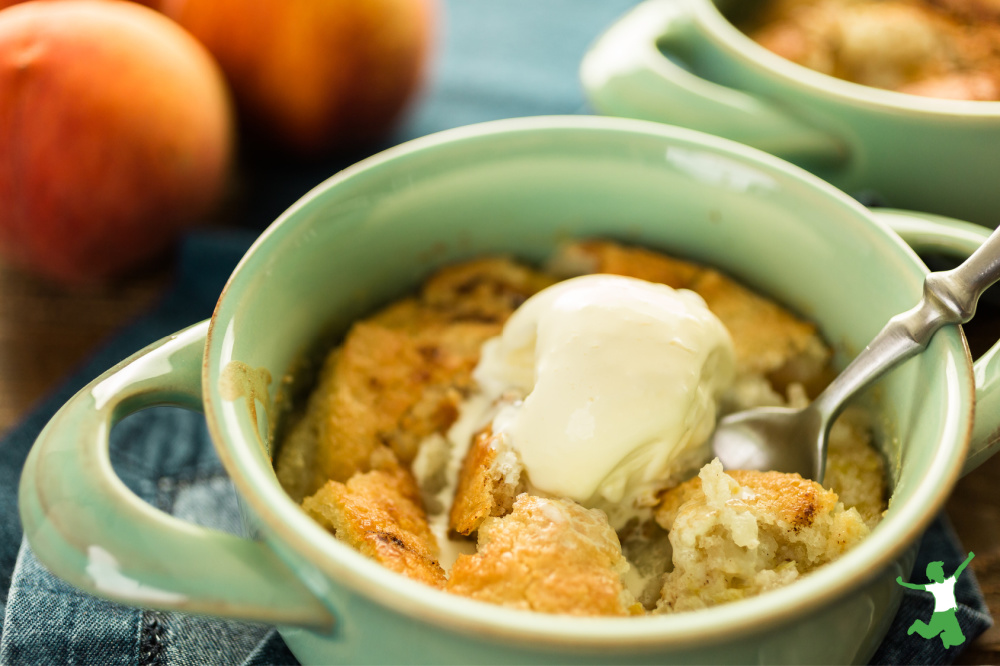 healthy grain free peach cobbler in a bowl with ice cream topping