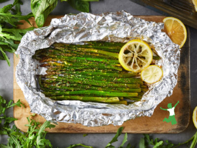 asparagus in aluminum foil on wooden cutting board
