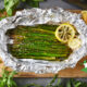 asparagus in aluminum foil on wooden cutting board