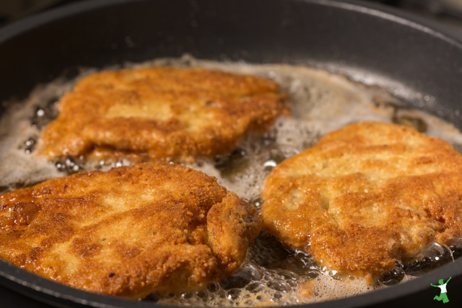 breaded beef heart sizzling in a pan on the stovetop