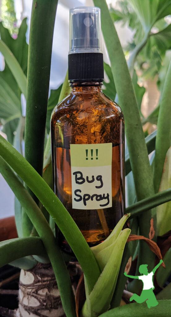 amber bottle if DIY bug repellent spray green foliage background