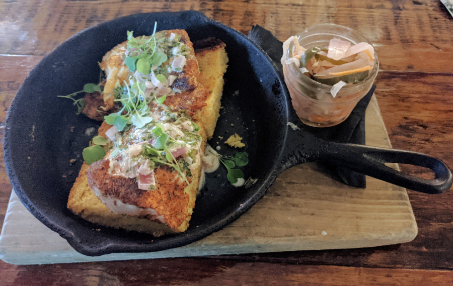 chimichurri sauce drizzled over flounder and cornbread in cast iron skillet