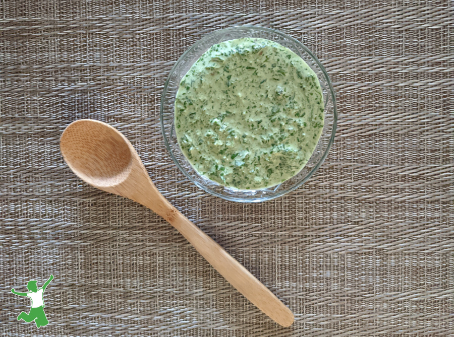 green chimichurri sauce in glass bowl with bamboo spoon