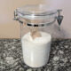 homemade green laundry powder in container with wooden scoop