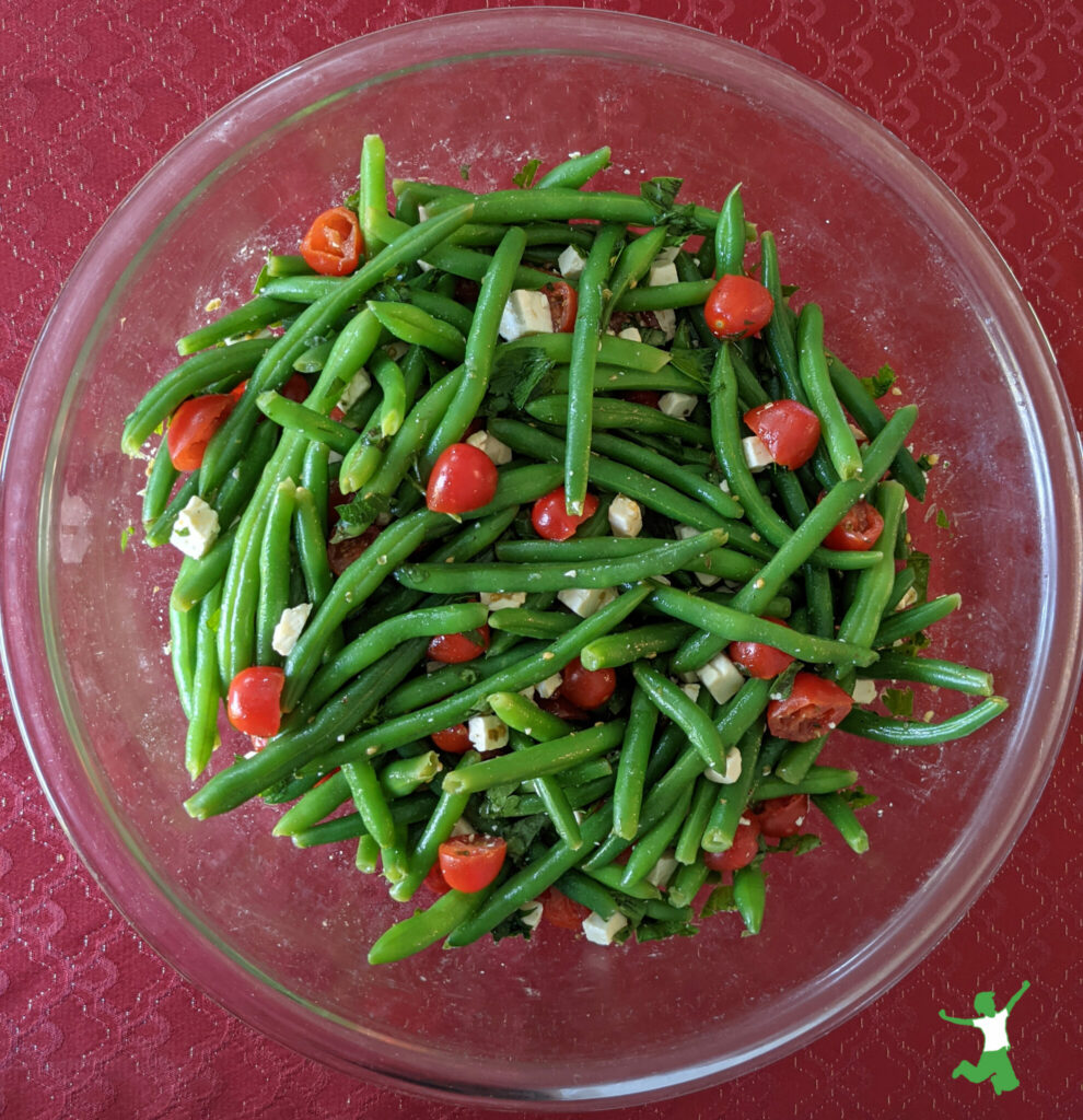 green bean and tomato "Christmas" salad in glass bowl on holiday tablecloth