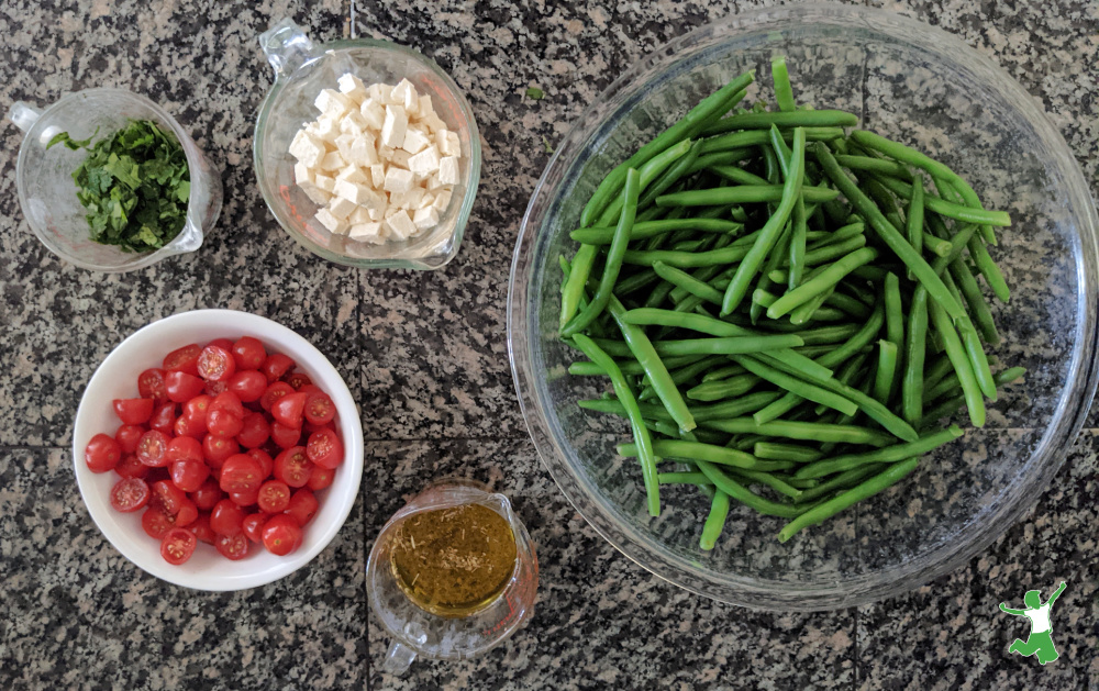 green bean, tomato and feta salad ingredients prepped on granite counter