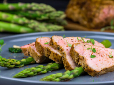pork tenderloin slices on blue plate with asparagus spears