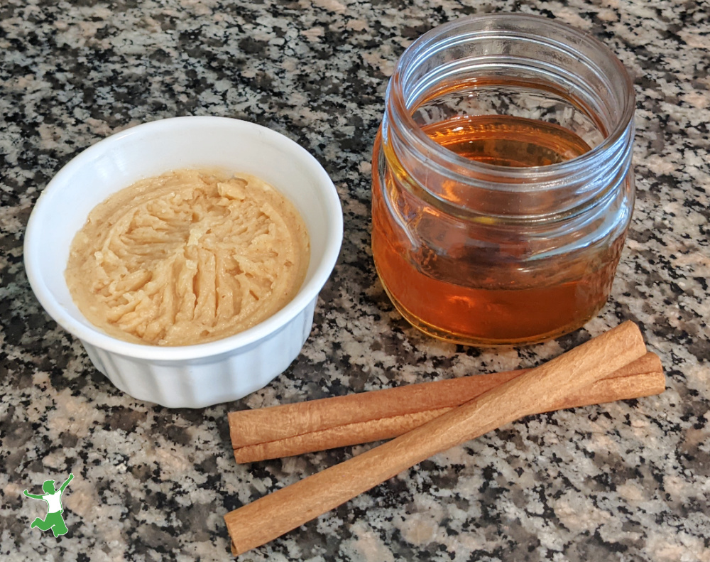 homemade cinnamon butter in small white bowl with honey and cinnamon sticks