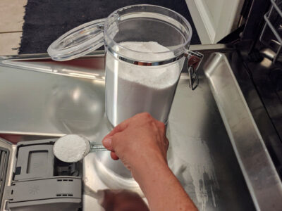 woman pouring DIY dishwasher powder into dispenser