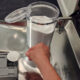 woman pouring DIY dishwasher powder into dispenser