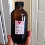woman holding amber bottle of homemade hawthorn heart syrup