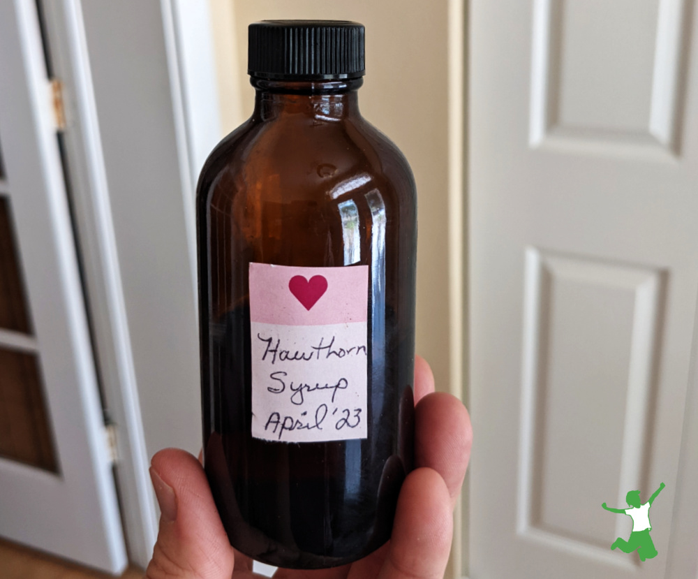 woman holding homemade hawthorn syrup in amber bottle