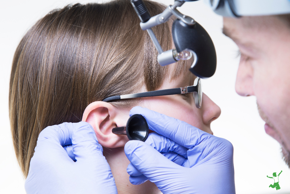 young girl being checked for ear tubes by doctor