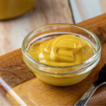 honey mustard salad dressing in glass bowl on wooden cutting board with fork