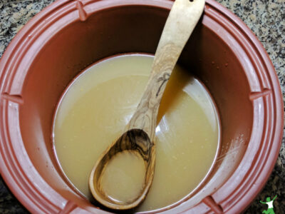 homemade broth with glutamate in clay stockpot with wooden ladle