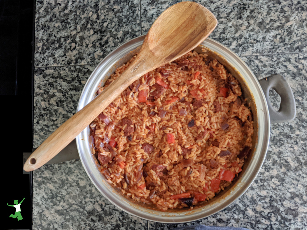 skillet of Cajun venison sausage on counter with wooden spoon