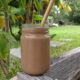 carob banana avocado smoothie in a glass with bamboo straw