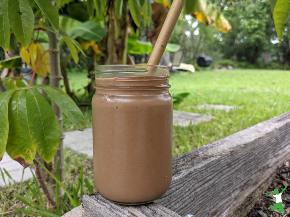 carob banana avocado smoothie in a glass with bamboo straw