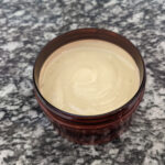 homemade vanilla body lotion in amber jar on granite counter