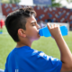 young boy drinking toxic blue sports drink at soccer game