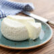 homemade ricotta cheese from raw milk on ceramic plate on wood table