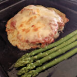 low carb chicken parmesan with asparagus spears on baking pan