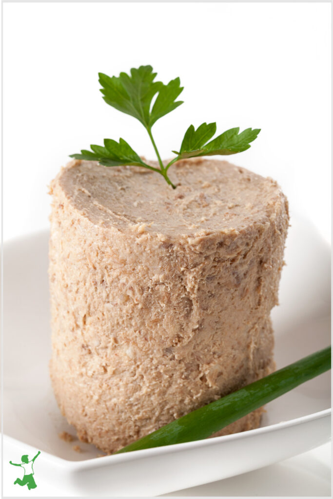 chicken liver and bacon pate on white plate with sprig of parsley