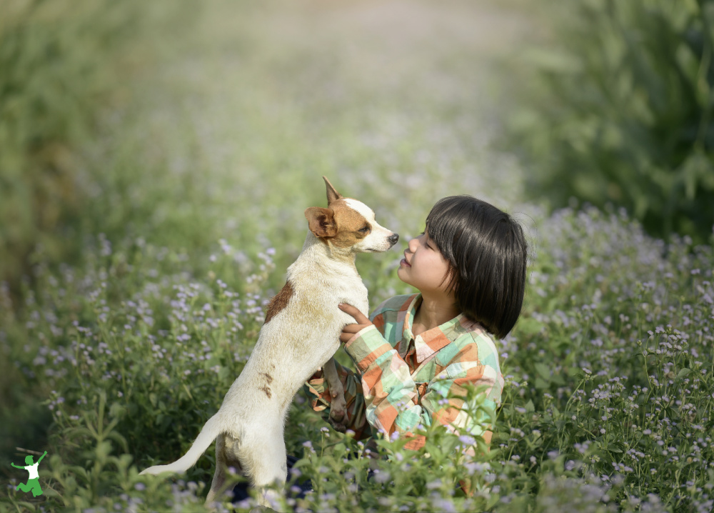 little girl with a pet dog in lush field full of flowers