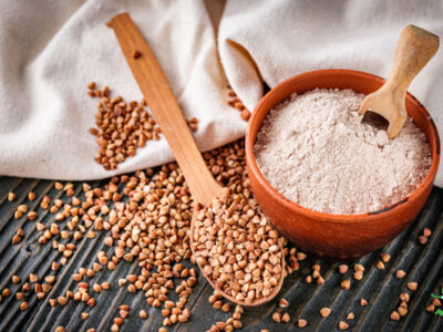 buckwheat groats and flour in clay bowl with white tablecloth