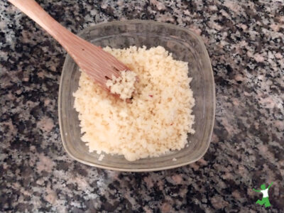 homemade shredded mozzarella cheese in a glass bowl on granite counter