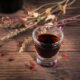 shot glass of herbal bitters on wood table for bile production and fat digestion