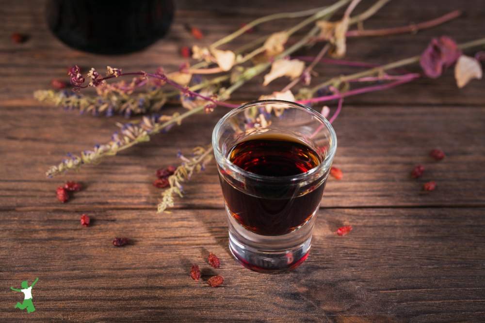 shot glass of herbal bitters on wood table for bile production and fat digestion