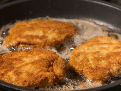 breaded beef heart sizzling in healthy fat in a pan