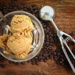 dairy-free coffee ice cream in glass bowl with decaf beans on wooden table