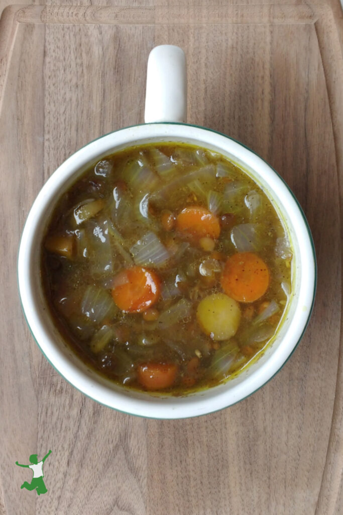 curry lentil soup in a mug on wood board