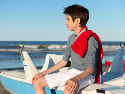 young man with gynecomastia at the beach