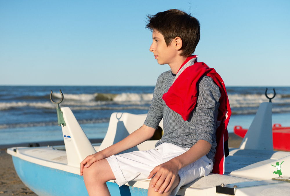 young man with gynecomastia at the beach