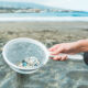woman with sieve of microplastics contamination at the beach