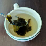 homemade dashi broth in a mug with kombu pieces