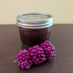 homemade American beautyberry jam in small mason jar with sprig of fresh berries