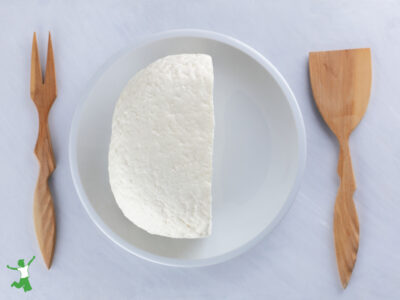 homemade kefir cheese on white plate with wood utensils