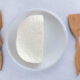 homemade kefir cheese on white plate with wood utensils